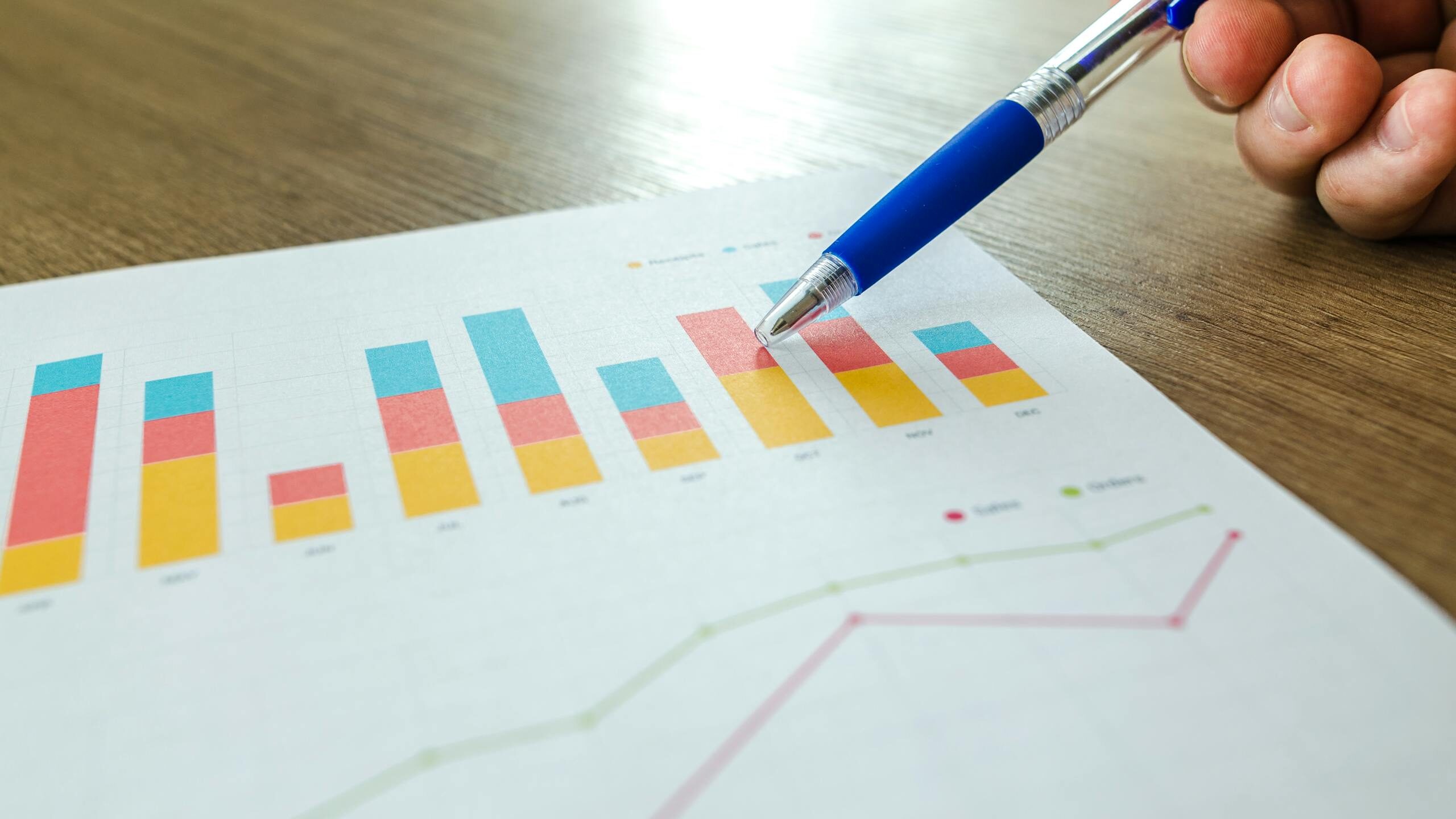 Person Holding Pen Pointing at Graph