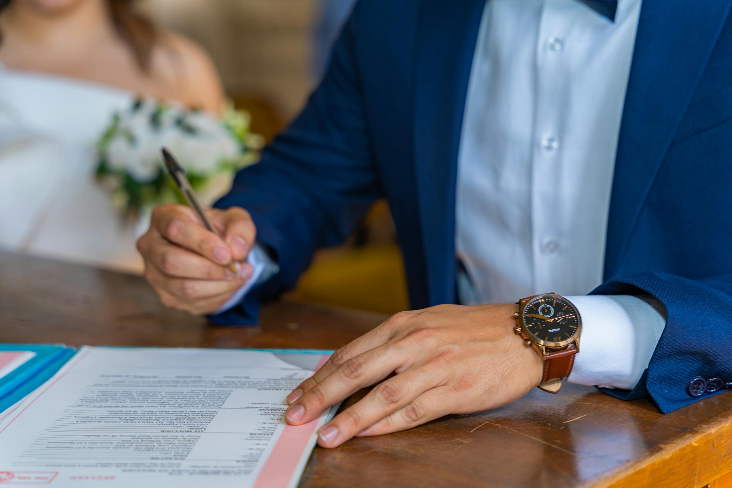 A man in a suit signing a document at a wedding